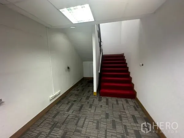 Office Space for rent in Khlong Toei, Bangkok - Internal staircase with red carpet in an office corridor with white walls and carpet flooring.