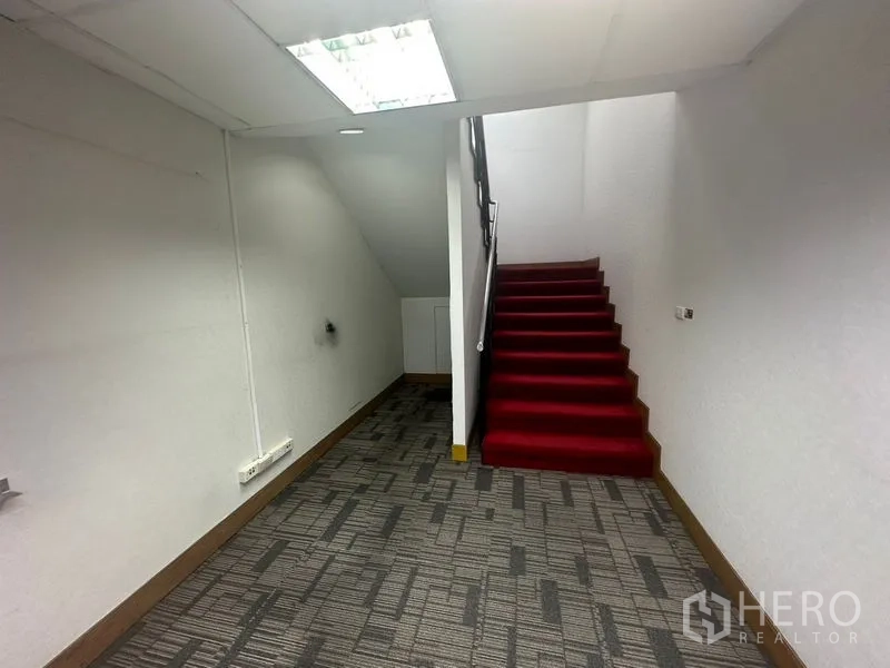 Office Space for rent in Khlong Toei, Bangkok - Internal staircase with red carpet in an office corridor with white walls and carpet flooring.