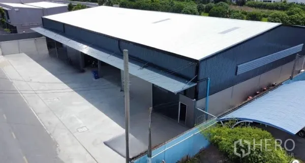 Warehouse for rent in Bang Bua Thong, Nonthaburi - Aerial view of a modern steel warehouse with a wide concrete loading apron and street access in Bang Bua Thong.