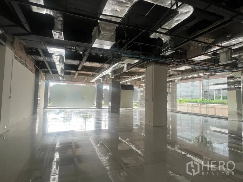 Retail Space for rent - Bright retail hall with reflective flooring, structural columns and natural light from large windows.