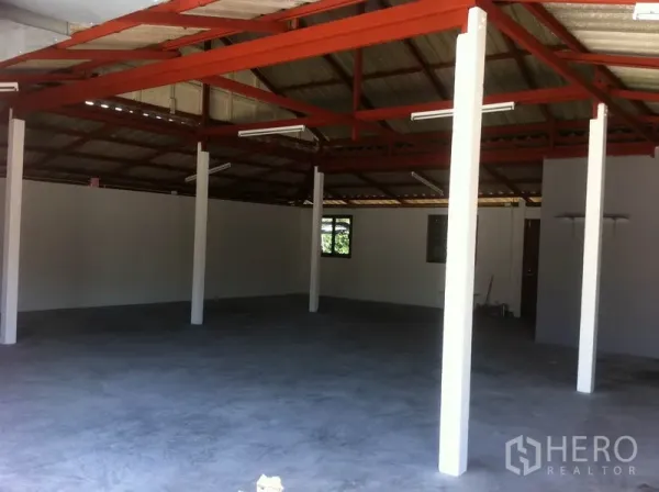 Warehouse for rent in Lam Luk Ka, Pathum Thani - Spacious open-plan warehouse interior with red steel roof trusses, white support columns, and a concrete floor.