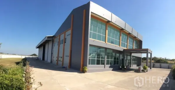 Factory for sale in Bang Sao Thong, Samut Prakan - Wide view of the factory building with large concrete apron and landscaped verge.