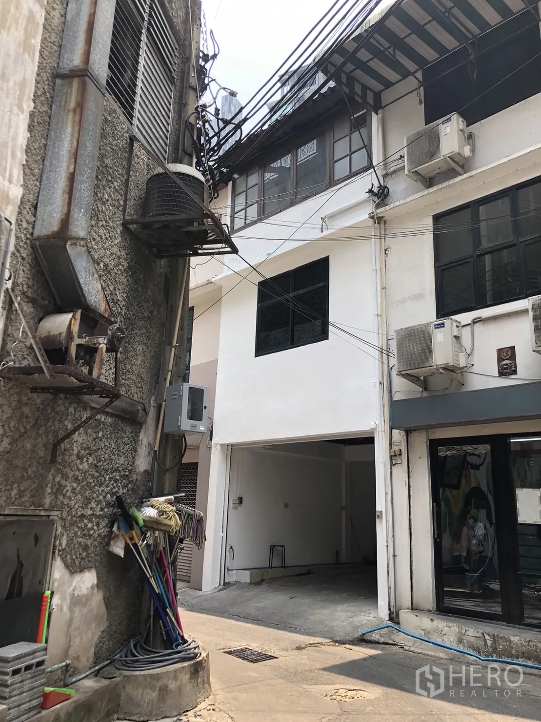 Shophouse for rent - Rear-lane exterior of white shophouse with upper windows and AC units.