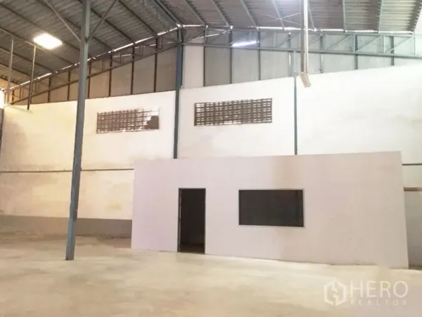 Warehouse for rent in Prawet, Bangkok - Warehouse interior featuring a built-in office room, metal roof structure, and polished concrete surface.
