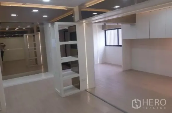 Retail Space for rent - Open-plan interior with recessed lighting, mirrored walls and a window bringing in daylight.