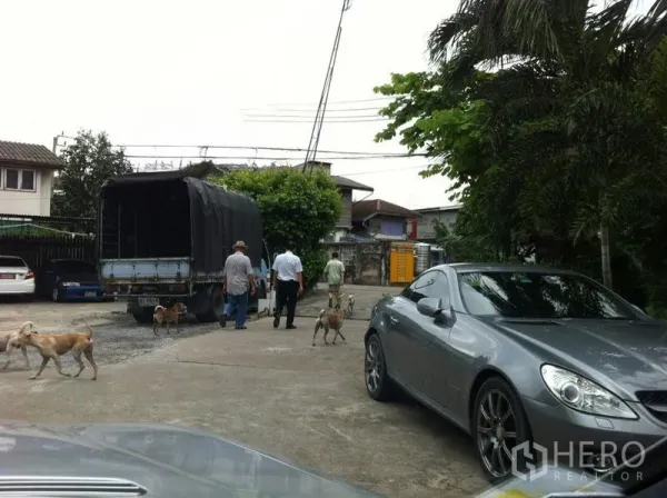 工厂 出租在Khlong San, Bangkok - 工厂园区入口的宽阔混凝土车道，停有卡车与轿车，周边有树木