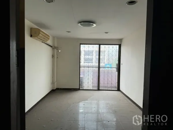 店屋 出租在Watthana, Bangkok - 未配家具的房间，瓷砖地面，墙挂空调，落地移门通向小阳台。