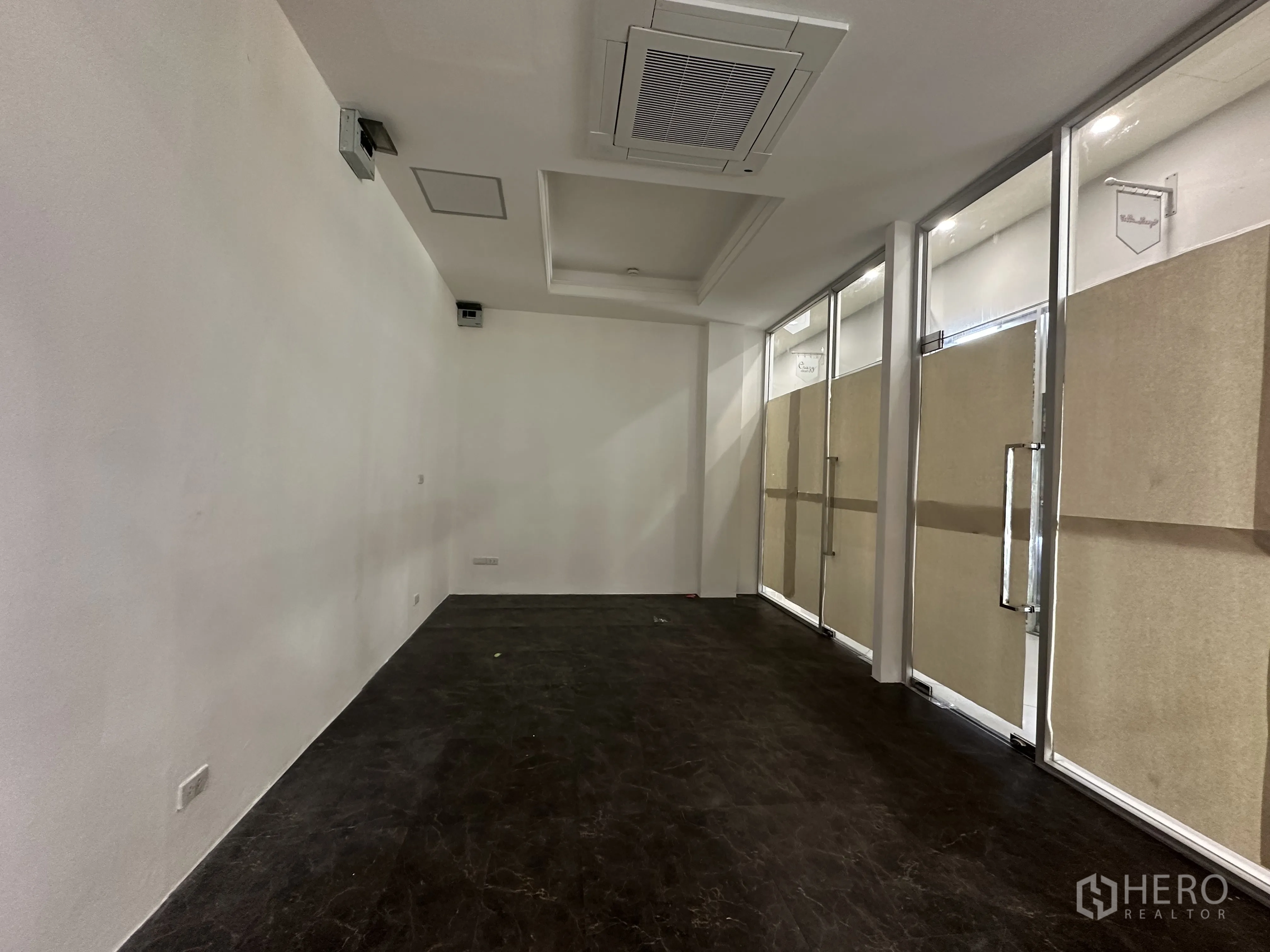 Retail Space for rent in Khlong Toei, Bangkok - Long interior of the retail space with recessed lighting, glass panels, and power outlets.