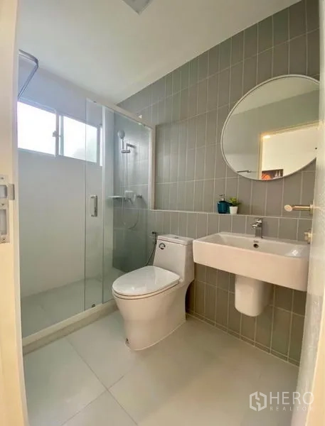 Townhouse for rent in Bang Phli, Samut Prakan - Clean bathroom with grey vertical tiles, round mirror and walk-in glass shower.