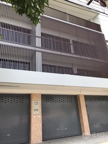 Shophouse for rent in Suan Luang, Bangkok - Modern shophouse facade with metal roller shutters and screened balconies.