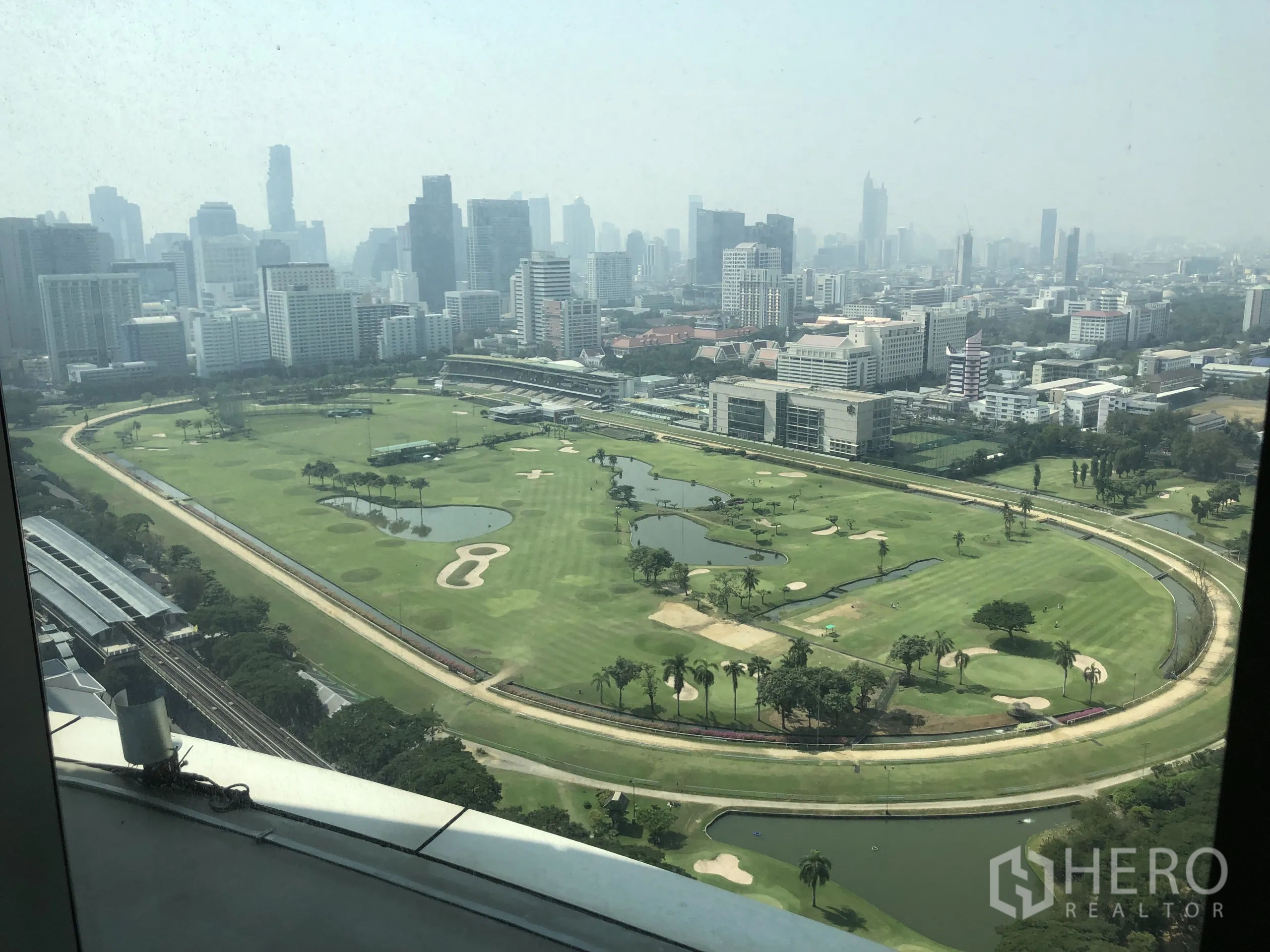 Condominium for rent in Pathum Wan, Bangkok - High-floor view of a green golf course and city skyline across Pathum Wan from the condo window.