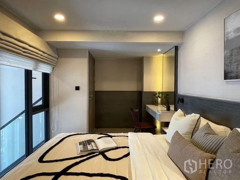 Condominium for rent in Pathum Wan, Bangkok - Cozy bedroom corner with bedside windows, built-in vanity desk and warm ambient lighting.