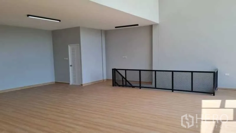 Warehouse for rent in Bang Bua Thong, Nonthaburi - Second-floor open-plan office with wood-look flooring and a black metal railing.
