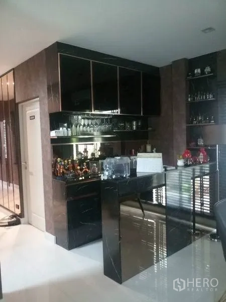 Detached House for sale in Nonthaburi - Built-in pantry and bar with glossy black cabinets and mirrored shelving.