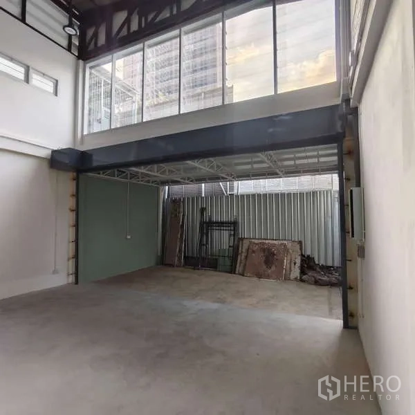 Shophouse for rent in Khlong Toei, Bangkok - Covered loading bay beneath mezzanine with tall front glazing.