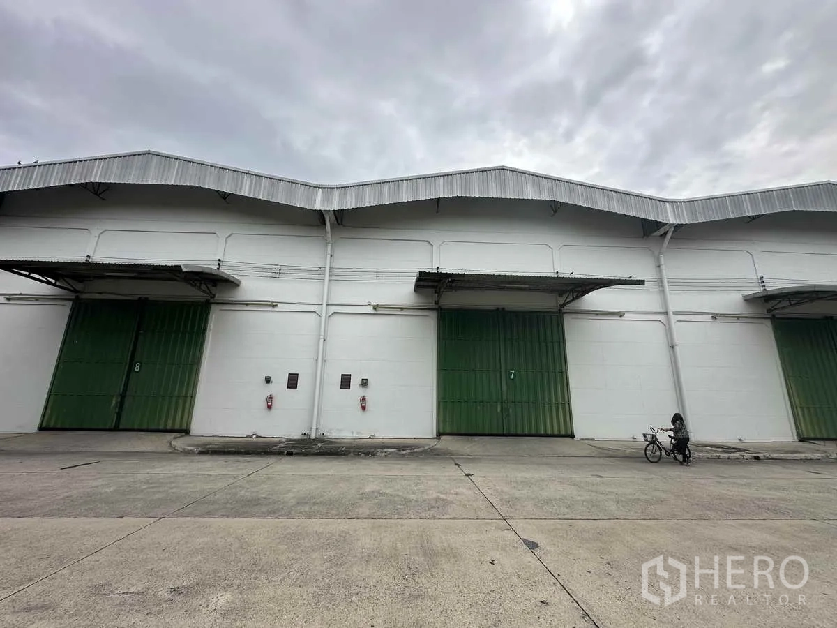 Warehouse for rent in Bang Pa-in, Phra Nakhon Si Ayutthaya - Front view of warehouse bays with large green roller doors and covered loading docks in an industrial compound.