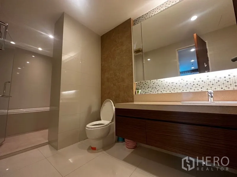 Condominium for rent in Khlong Toei, Bangkok - Contemporary bathroom with long vanity, toilet and separate shower enclosure.