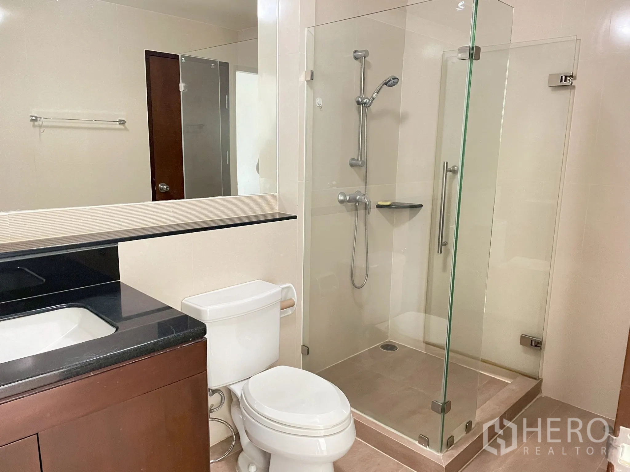 Apartment for rent in Khlong Toei, Bangkok - Bathroom with glass-enclosed shower, vanity, and toilet.