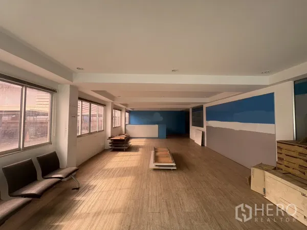 Factory for rent in Phra Pradaeng, Samut Prakan - Ground floor office area with large windows, dropped ceiling and wood‑tone flooring.