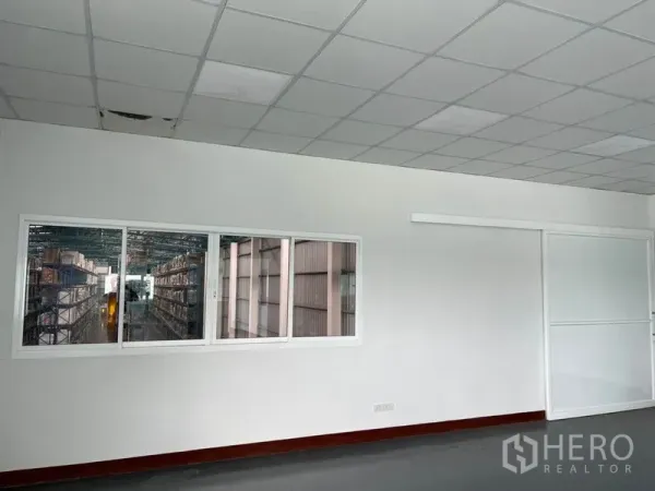 货栈 出租在Lat Krabang, Bangkok - 办公室观景窗，可看到仓库内的货架通道