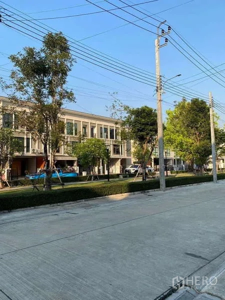 联排别墅 出租在Bang Kapi, Bangkok - 林荫内部道路，两侧现代联排与小绿化带。