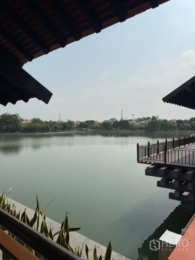 Detached House for rent or sale in Mueang Nonthaburi, Nonthaburi - Serene lakeside view with boardwalk and railing within the estate.