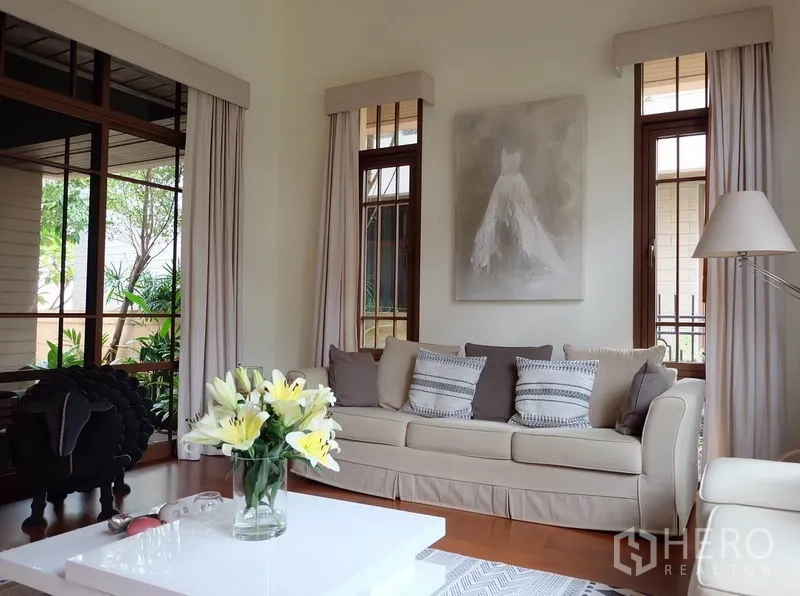 Detached House for rent in Watthana, Bangkok - Alternate view of the bright living room with neutral sofa, white coffee table, and fresh flowers.