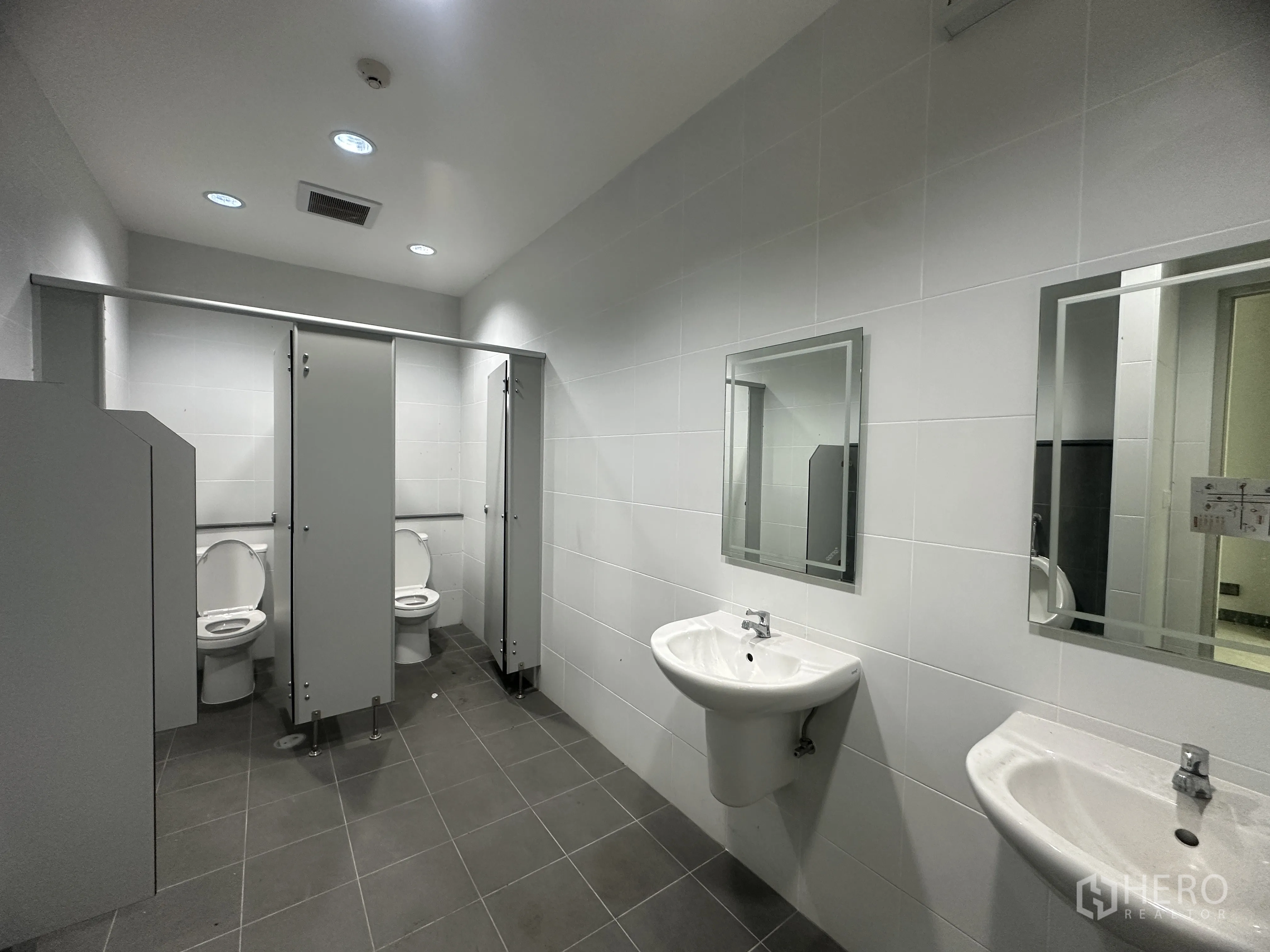 Warehouse for rent in Mueang Chon Buri, Chon Buri - Clean restroom with cubicles, sinks, mirrors, and tiled finishes.