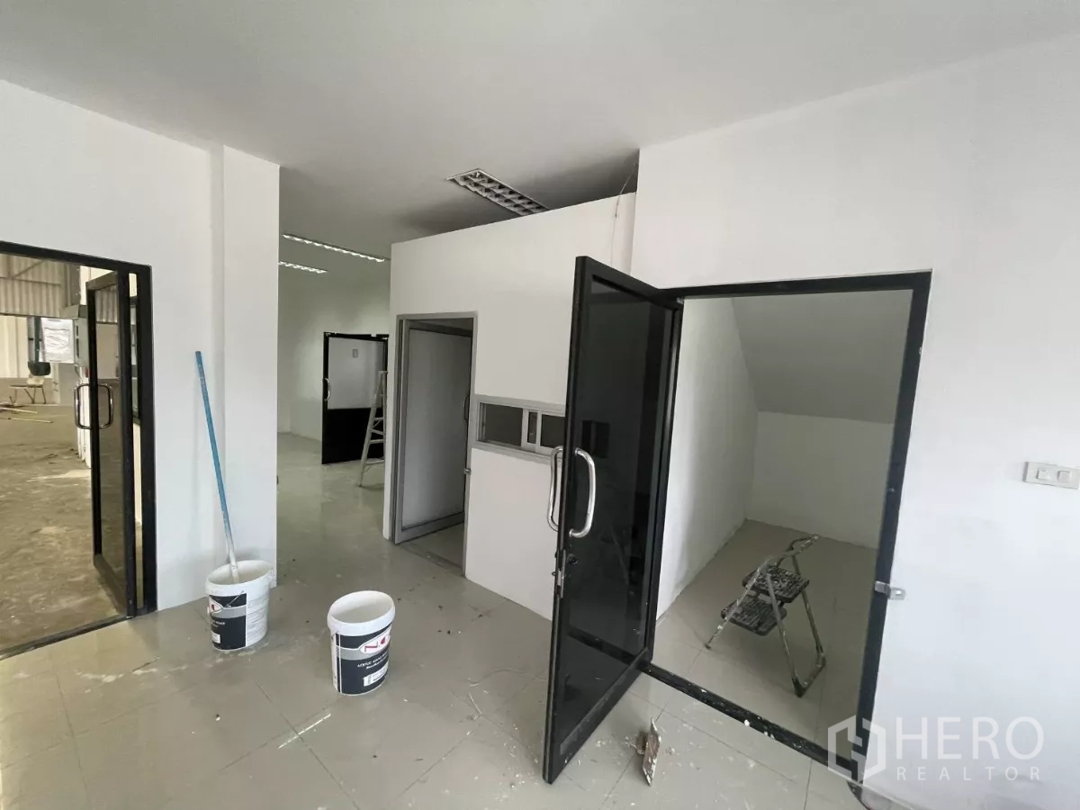 Warehouse for rent in Lat Krabang, Bangkok - Ground-floor office area with glass doors, tiled floors, and a small storage room.