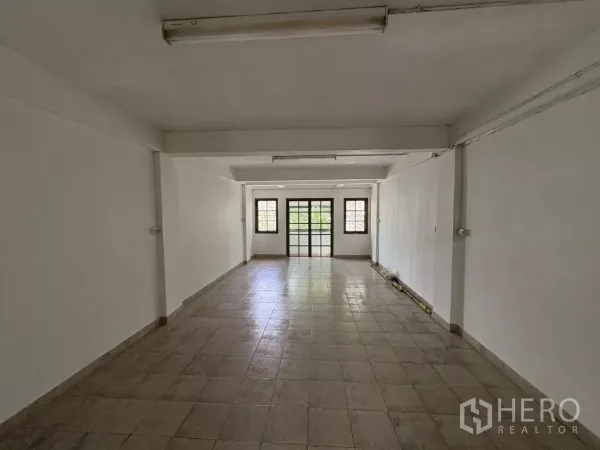 Shophouse for rent in Phra Khanong, Bangkok - Large open‑plan floor with ceramic tiles, white walls and windows at the far end.