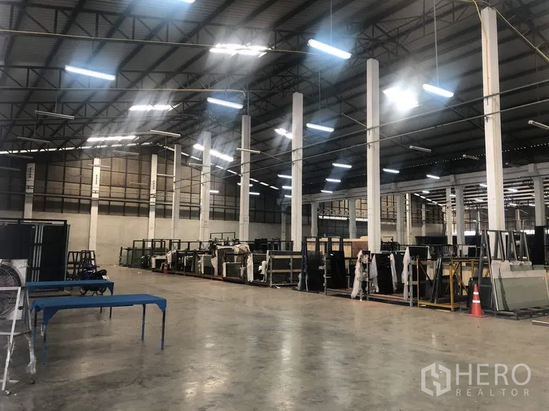 Warehouse for rent in Nonthaburi - Spacious warehouse interior with high steel roof, white columns and bright LED lighting.