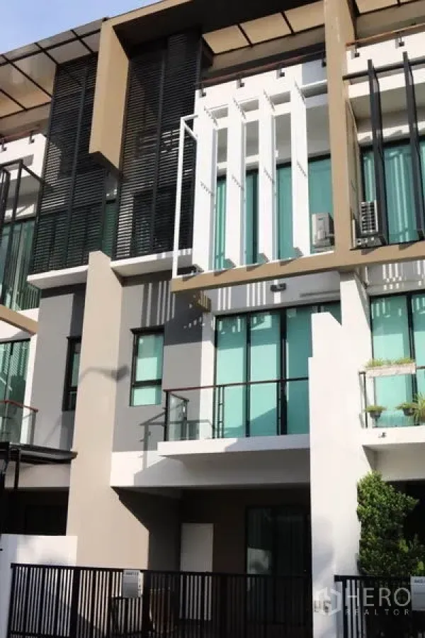 Townhouse for rent in Khlong Toei, Bangkok - Contemporary three-storey townhouse facade with glass balconies, sunshades and vertical louvers.