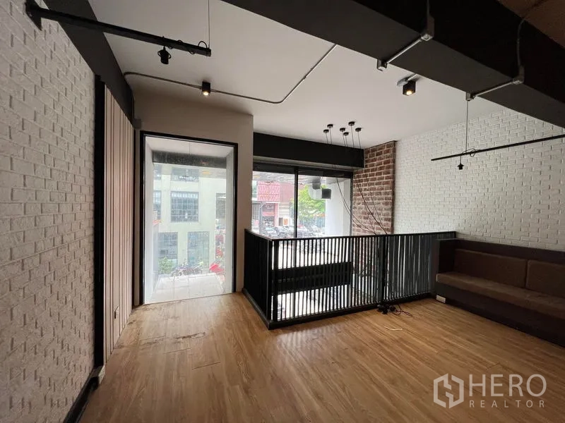 Shophouse for rent - Mezzanine seating area with railing, brick accent wall and street-view windows.