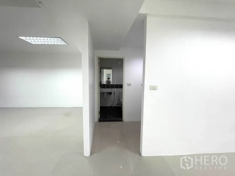 Office Space for rent in Khlong Toei, Bangkok - Entrance to the restroom from the open office area with white partitions.