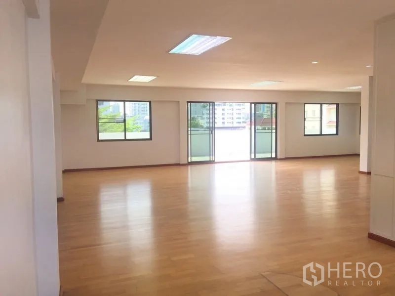 Home Office for rent in Watthana, Bangkok - Large room with wood flooring and sliding doors opening to a balcony.