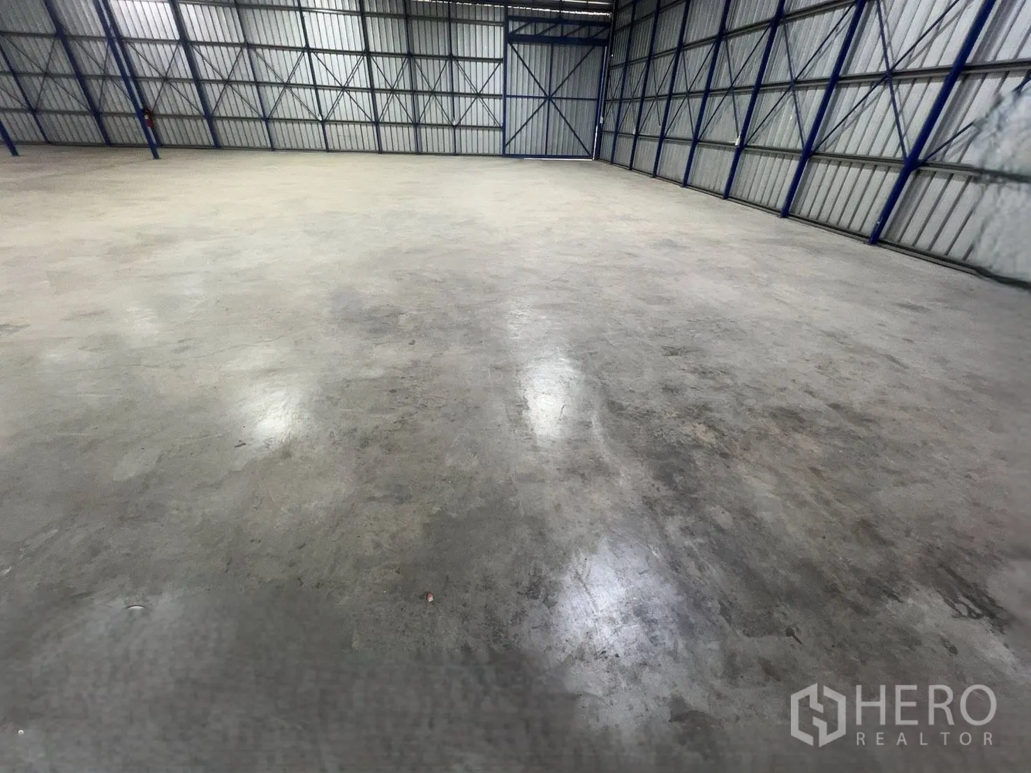 Warehouse for rent in Khlong Luang, Pathum Thani - Close view of the warehouse’s concrete floor and metal wall structure.
