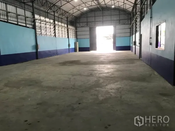 Warehouse for rent in Khlong Luang, Pathum Thani - Open-plan storage hall facing the loading door with natural light and visible power points.