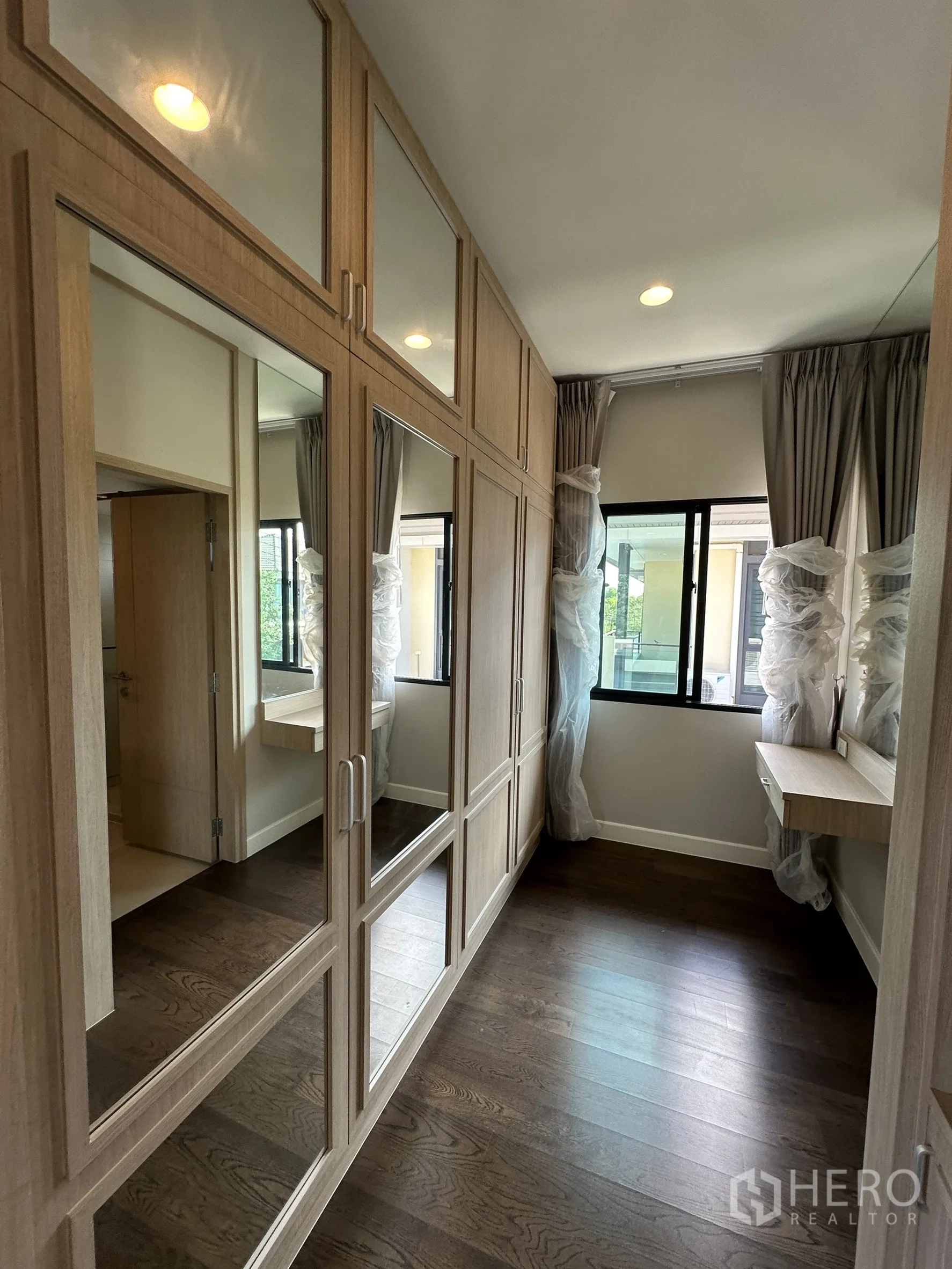 Detached House for sale in Lam Luk Ka, Pathum Thani - Walk-in closet with mirrored wardrobes, dressing table and windows.