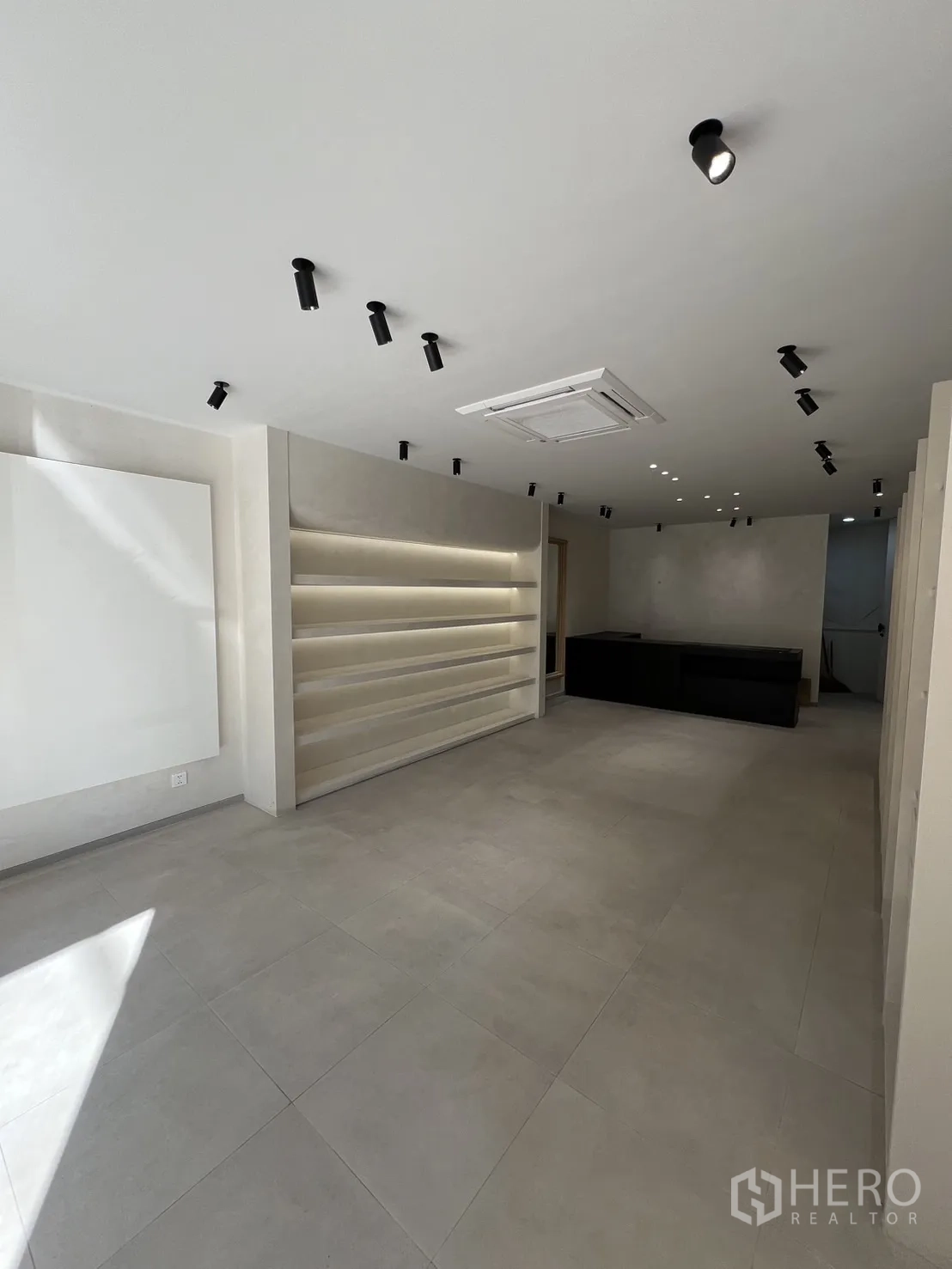Retail Space for rent in Bangkok - Minimalist retail interior with tiled floor, ceiling spotlights and illuminated display shelves