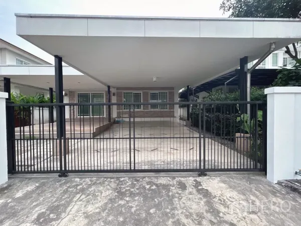 Detached House for sale in Bang Kapi, Bangkok - Close-up of the secure sliding gate and expansive covered parking area for multiple cars.