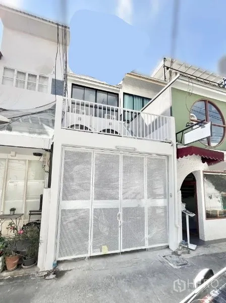 Home Office for rent in Khlong Toei, Bangkok - Front elevation of renovated home office with white mesh sliding gate and balcony.