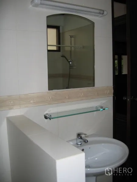 Detached House for rent in Watthana, Bangkok - Vanity area with sink, mirror and glass shelf in the bathroom.
