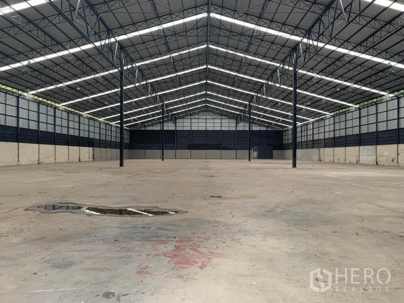 Factory for rent in Chon Buri - Wide empty concrete hall with evenly spaced columns and long ridge skylights.
