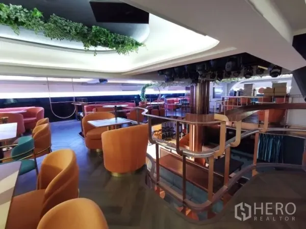 Retail Space for rent - Curved staircase and railings leading to a greenery-accented mezzanine with lounge seating.
