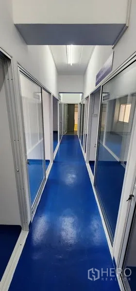 Warehouse for rent in Bueng Kum, Bangkok - Long hallway with fluorescent lighting and glass rooms on both sides.