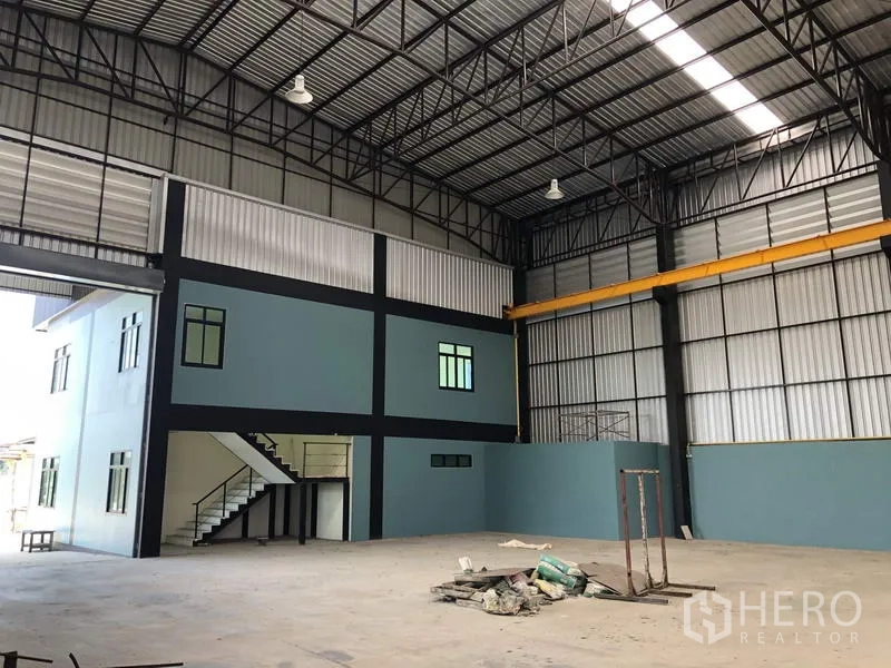 Factory for rent in Lam Luk Ka, Pathum Thani - Spacious factory interior showing high-clearance steel trusses, crane rails and a two-storey office block.