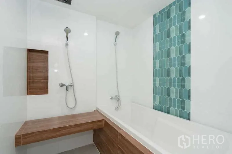 Apartment for rent in Khlong Toei, Bangkok - White bathroom with bathtub, twin shower heads and wood-look shelving.