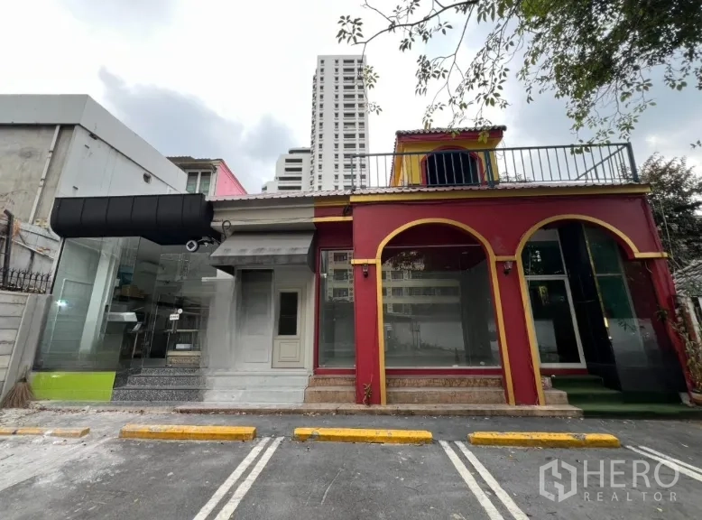 Retail Space for rent in Watthana, Bangkok - Street-facing retail unit with red arched facade, large glass windows and marked parking spaces in front.