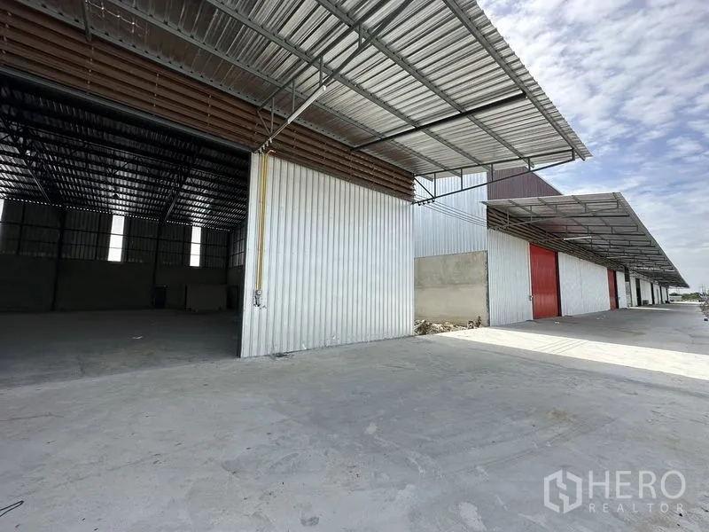 Warehouse for rent in Lam Luk Ka, Pathum Thani - New warehouse exterior in Lam Luk Ka with wide metal canopy, large sliding door and concrete loading apron.