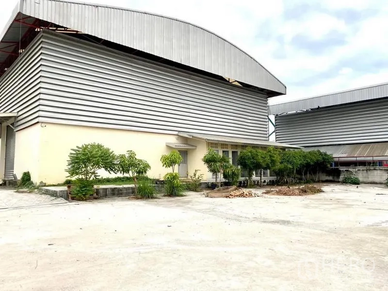 Warehouse for rent in Lam Luk Ka, Pathum Thani - Warehouse exterior with metal cladding and a small landscaped garden strip.
